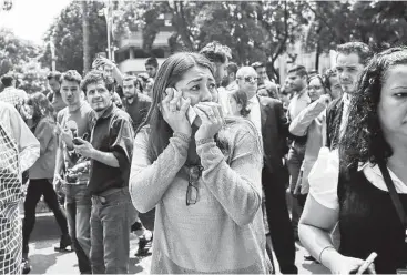  ?? Rebecca Blackwell / AP ?? Una mujer trata de hablar por su teléfono celular mientras la gente se reúne en la avenida Reforma después del poderoso terremoto que se sintió en la Ciudad de México el martes 19 de septiembre de 2017.