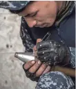  ?? CARL COURT, GETTY IMAGES ?? An Iraqi federal policeman writes a Shiite religious blessing on a mortar before firing it Wednesday at an Islamic State position in Mosul, Iraq.