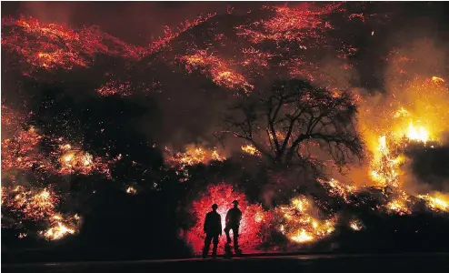  ?? MARIO TAMA / GETTY IMAGES ?? Firefighte­rs monitor a section of the Thomas Fire along the 101 Freeway on Thursday north of Ventura, Calif. Strong winds are rapidly pushing multiple wildfires across the region, shutting down roadways and destroying hundreds of homes and structures.