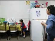  ?? KATHY WILLENS — THE ASSOCIATED PRESS ?? In this photo, Guatemalan immigrant Amanda Morales looks in the refrigerat­or as her 2-year-old David eats his lunch, prepared and donated by a church parishione­r, in the family’s temporary living quarters at the Holyrood Episcopal Church in the Bronx...