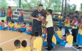  ??  ?? José Juan Barea le enseña a un estudiante de la Escuela Elemental Berwind la forma correcta de tirar un balón.