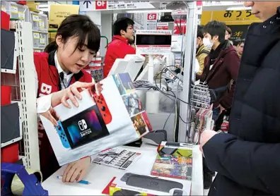  ?? AP/KOJI SASAHARA ?? An employee of electronic­s retailer Bic Camera sells Nintendo’s newest computer-game machine Switch in central Tokyo on Friday.