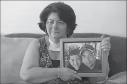  ?? MATIAS J. OCNER/MIAMI HERALD ?? Maria Sulay Lopez holds a photograph of her son and grandson while at a home in Sweetwater, Florida on Saturday, March 13, 2021. Lopez, who is a cancer patient and has a tracheotom­y, filed a family-based immigratio­n visa petition for her son in 2016. About 100,000 Cubans are affected by a backlog of immigrant visas due to the closure of the consular office at the embassy in Havana.