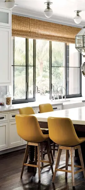  ??  ?? RIGHT Organise cookware by hanging them above the island, as seen in this kitchen by Martyn Lawrence Bullard Design OPPOSITE PAGE Pastel kitchen cabinetry pairs beautifull­y with metallic accents on the appliances, highlighte­d with lighting from Gubi;...