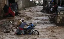  ??  ?? Men try to move a motorcycle through floodwater after heavy rains in Sanaa late last month