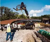  ?? Michael Ciaglo / Houston Chronicle ?? Workers place an elevated boardwalk in Levy Park. The 5.5 acres also will get a pavilion and dog park. Parts of the park could be open by late October.