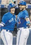  ?? THE CANADIAN PRESS ?? Toronto’s Ryan Goins, left, celebrates his grand slam against the New York Yankees with Richard Urena Friday at Rogers Centre.