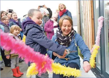  ??  ?? Primary one pupil, Fionn Togher, five, cuts the ribbon to mark the opening of the new Strontian Primary School this week, watched by head teacher Pamela Hill.