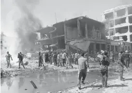  ?? DELIL SOULEIMAN/AGENCE FRANCE-PRESSE VIA GETTY IMAGES ?? Residents gather at the site of a bomb attack in Syria's northeaste­rn city of Qamishli on Wednesday. A massive bomb blast killed at least 67 people and wounded more than 185.