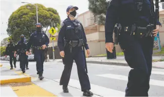  ?? Jessica Christian / The Chronicle 2020 ?? S.F. police officers monitor a street. A bill in the Assembly would decriminal­ize jaywalking.