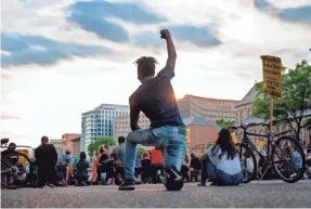  ?? JIM WATSON/AFP VIA GETTY IMAGES ?? A protester kneels and holds up a fist as he and others demonstrat­e the death of George Floyd by locking traffic in Washington, D.C.