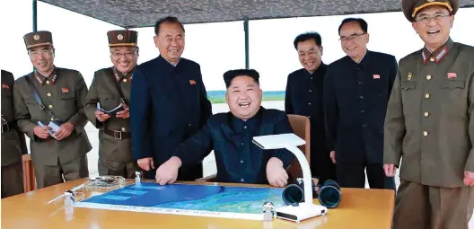  ??  ?? War games: Kim Jong-un, surrounded by fawning flunkies, during the launch of the missile that passed over Japan