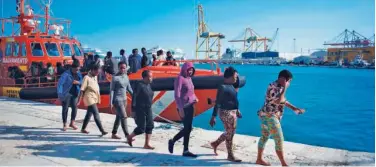  ?? Agence France-presse ?? ↑
Migrants walk in a single line upon their disembarkm­ent at the harbour of Malaga on Tuesday.