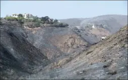  ?? The Associated Press ?? A home, at left, stands alone among the devastatio­n left behind by a wildfire Monday in Malibu, Calif.