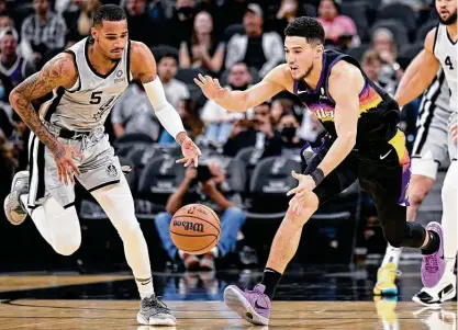  ?? Darren Abate / Associated Press ?? Do-it-all point guard Dejounte Murray, chasing down a loose ball against the Suns’ Devin Booker on Monday at the AT&T Center, has been filling up the stat sheets like few in Spurs history. But the club is struggling to translate those numbers into victories.