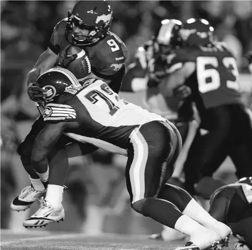  ?? JEFF MCINTOSH/ THE CANADIAN PRESS ?? Edmonton Eskimos defensive lineman Alex Daniels tackles Stampeders tailback Jon Cornish in Calgary on Friday night. Cornish rushed for 180 yards and two touchdowns in Calgary’s 39-15 romp over the slumping Eskimos.