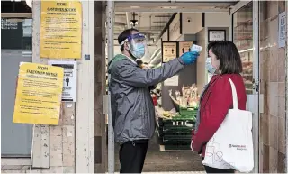  ?? DAN KITWOOD GETTY IMAGES ?? A woman has her temperatur­e checked before entering a supermarke­t in London on Thursday.