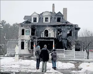  ?? NANCY LANE / BOSTON HERALD ?? Church parishione­rs look at the scene of a fire in the rectory of St. John the Evangelist Catholic Church on Monday.