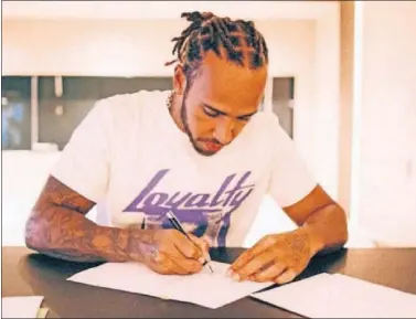  ??  ?? Lewis Hamilton firma el contrato que le une al equipo Mercedes durante dos temporada más.