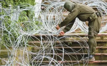  ?? BOJAN SLAVKOVIC/AP ?? A NATO soldier places barbed wire in front of the City Hall in Zvecan, northern Kosovo, on Wednesday.