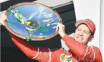  ?? Picture: AFP ?? FIRST BLOOD. Ferrari’s German driver Sebastian Vettel celebrates with the trophy on the podium after winning the Australian Grand Prix in Melbourne yesterday.