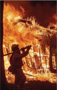  ?? AP/NOAH BERGER ?? Firefighte­r Jose Corona watches a house go up in flames as he sprays water on it Friday in Magalia in Northern California. The town is north of Paradise and was threatened by the same wildfire.