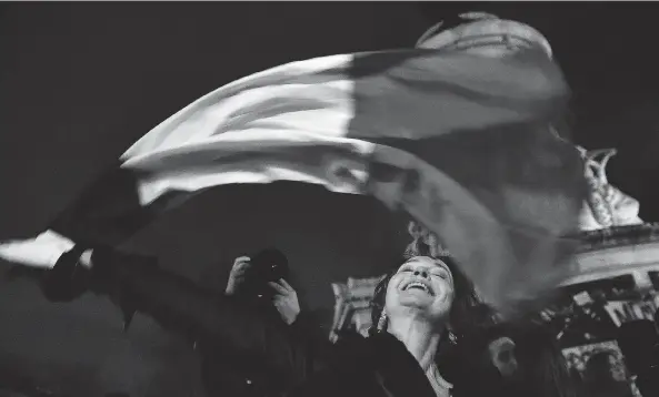  ?? PASCAL LE SEGRETAIN / GETTY IMAGES ?? A woman waves a French flag in Paris on Friday. Following the terrorist attacks last week, which claimed 130 lives, people continued to mark their solidarity with the victims.