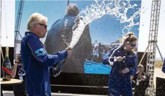  ?? AP ?? UP AND DOWN: Virgin Galactic founder Richard Branson sprays Champagne on crew member Beth Moses while celebratin­g a flight to space and back on Sunday. Virgin Galactic stock took a sharp turn lower after the company said it plans to sell $500 million in additional shares.