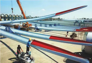  ?? AFP ?? ■ Workers check the quality of newly manufactur­ed wind turbine blades at a factory in Lianyungan­g in China’s eastern Jiangsu province. Chinese factory activity slowed in July, missing forecasts as extreme weather and a trade war with the US weighed on...