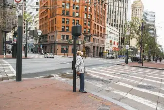  ?? Gabrielle Lurie / The Chronicle 2020 ?? Though cars were nearly absent on San Francisco streets during the early days of the pandemic, a pedestrian waits for the light to change. The coronaviru­s threat has upended our way of life.