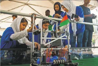  ?? Paul J. Richards / AFP / Getty Images ?? Members of the Afghan robotics team work with their device in a practice area of the FIRST Global Challenge in Washington, D.C. The girls were initially denied visas to travel to the U.S.