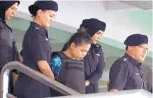  ?? KYODO NEWS ?? Indonesian Siti Aisyah, center, one of the two women accused of poisoning the half brother of North Korea’s leader, is escorted out of court in Shah Alam outside Kuala Lumpur Friday.