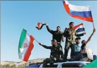  ?? OMAR SANADIKI / REUTERS ?? Syrians wave Iranian, Russian and Syrian flags during a protest against US-led airstrikes in Damascus on Saturday.