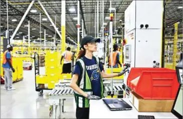  ?? BRYAN ANSELM/THE NEW YORK TIMES ?? Nissa Scott, 21, watches over a robotic arm stacking containers filled with merchandis­e at an Amazon warehouse in Florence, New Jersey, on August 29.