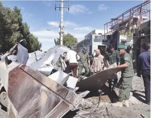  ?? (Reuters) ?? IRANIAN OFFICIALS survey the wreckage from a suicide car bomb that detonated outside a police station in Chabahar yesterday.