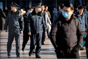  ?? (AP/Mark Schiefelbe­in) ?? A security officer wears a mask Monday as he patrols outside of the Beijing Railway Station.