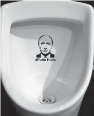  ??  ?? A picture taken on Friday shows a sticker bearing a picture of Russian President Vladimir Putin and insulting words on a urinal in the toilet of a popular restaurant in the Ukrainian city of Lviv. —