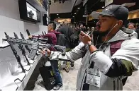  ?? ?? Paulo Rubio, of Canada, looks at a short-barreled rifle at the Sig Sauer booth at the 2018 National Shooting Sports Foundation's Shooting, Hunting, Outdoor Trade Show at the Sands Expo and Convention Center on Jan. 23, 2018, in Las Vegas. (Ethan Miller/ Getty Images/tns)