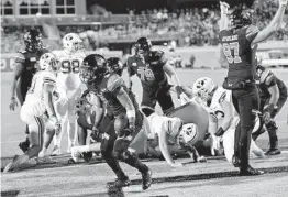  ?? RICHARD SHIRO AP ?? Coastal Carolina’s Reese White (center) scores a touchdown during the first half against BYU on Saturday. Both teams were 9-0 coming into the game.