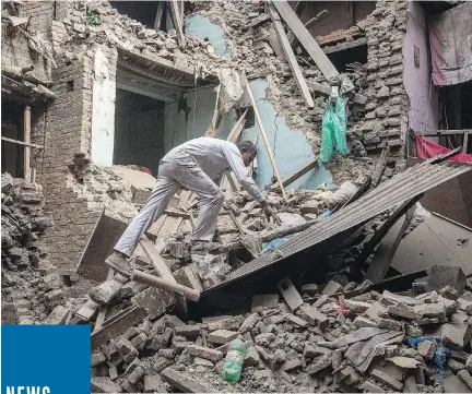  ?? OMAR HAVANA/GETTY IMAGES ?? A man climbs on top of debris after buildings collapsed in Bhaktapur, Nepal. Many houses, buildings and temples were destroyed during the earthquake Saturday, leaving thousands dead or trapped under the debris as emergency rescue workers race to find survivors.