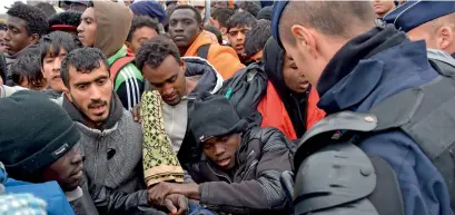  ?? AFP ?? French riot police officers jostle with hundreds of migrants as they start to clear the camp at Calais on Monday. —