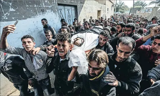  ?? HAITHAM IMAD / EFE ?? Palestinos portando ayer el cadáver de un miembro de las brigadas Al Nasser Salah al Deen, durante su funeral en la ciudad de Khan Yunis, Gaza