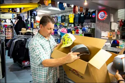  ??  ?? Brett Driscoll, owner of Driscoll’s Sports, works to remove new hats from boxes to display inside his store, located at West Main Street in El Centro, in November. Driscoll believes employers need to know who they are hiring. VINCENT OSUNA FILE PHOTO