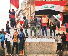  ?? AP ?? Anti-government protesters gather on barriers set up by security forces to close Rasheed Street during ongoing protests in Baghdad on Tuesday.