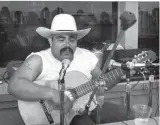  ?? COURTESY OF RAMON “CHUNKY” SANCHEZ ?? Ramon “Chunky” Sanchez singing with his guitar at microphone, circa 1974.