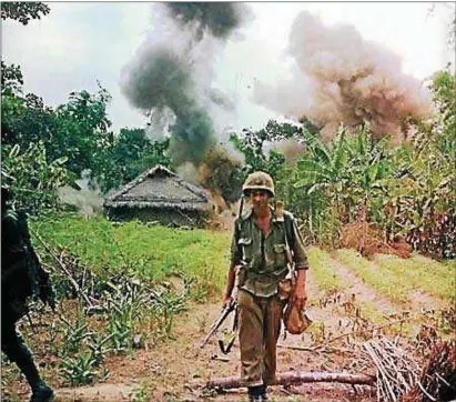  ??  ?? A soldier walks along a path as smoke rises behind him during the Vietnam War.