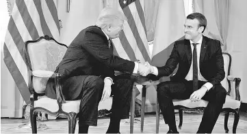  ??  ?? Mouth clenched and eyes fixed, Macron takes on Trump handshake before a working lunch ahead of the Nato Summit. — Reuters photo