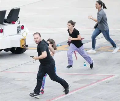  ??  ?? People run on the tarmac at Fort Lauderdale airport on Friday after a shooter opened fire inside a terminal. WILFREDO LEE / THE ASSOCIATED PRESS
