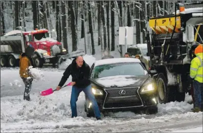  ?? The Associated Press ?? MAJOR DELAYS: An unidentifi­ed driver shovels a path for the driver of a car stuck and blocking the ramp from I-40 westbound to Cary Towne Blvd. on Sunday in Cary, N.C.