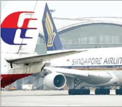  ?? LAURENT FIEVET/AFP ?? A Singapore Airlines A380 plane taxies past the tail of a Malaysia Airlines Boeing 737 at Hong Kong Internatio­nal Airport.